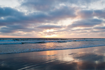 The sun setting over the Pacific ocean seen from a beach in summertime in southern California, USA