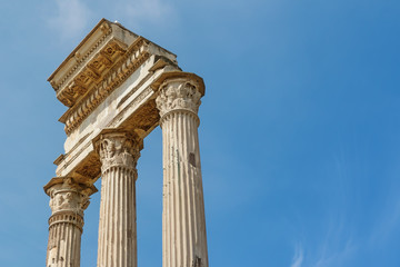 Ruins of the iconic three columns in Forum Romanum with free place for your text. Rome. Italy. Blue sky on the background. Horizontally.