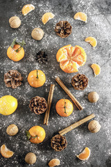 Christmas background with tangerines, pine cones, nuts, snow, and cinnamon sticks