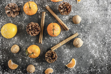 Christmas background with tangerines, pine cones, nuts, snow, and cinnamon sticks