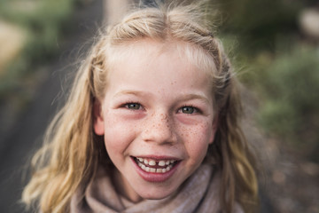 Portrait of smiling girl with blond hair standing in forest
