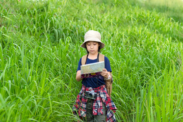 Kid girl holding maps and camera for travel backpacks walking survey in the meadow forest for education nature on vacations summer time. Travel Concept.