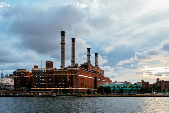 Factory By East River In City Against Cloudy Sky