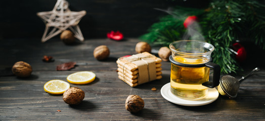 hot steamy tea on wooden table with blurred christmas decorated background