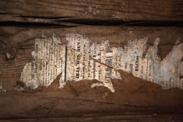 Scraps of old newspapers on the walls. A 19th century newspaper on the walls of an old wooden house.