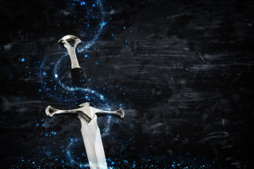 low key image of silver sword with magical lights. fantasy medieval period.