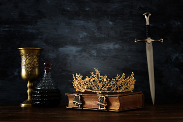 low key image of beautiful queen/king crown, wine cup and sword. fantasy medieval period.
