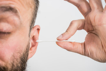 Man removing wax from ear using Q-tip