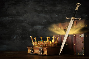 low key image of beautiful queen/king crown, open chest with treasure and sword. fantasy medieval period.