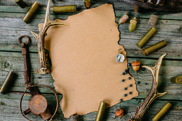 Closeup paper for information on old wooden background and deer horn, trap and cartridges beside....
