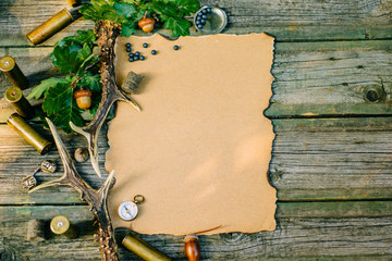Closeup vintage sheet of paper for information with hunting equipment from left side on old wood...