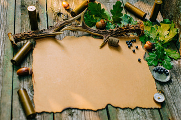 Closeup vintage sheet of paper with hunting equipment from left side on old wood board