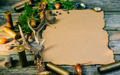 Closeup vintage sheet of paper with hunting equipment from left side on old wood board