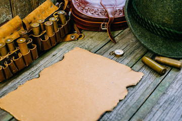 Vintage paper in the center of hunting equipment, oak and horns around of old wood board. side view