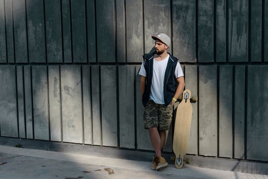 Young Man With Skateboard Leaning On Wall