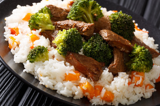Roasted beef with broccoli with rice and persimmon side dish close-up on a plate. horizontal
