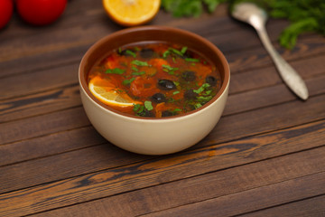 Solyanka soup with lemon, meat, pickles, tomato sauce and olives Traditional Russian dish solyanka. Solyanka soup with lemon, meat, pickles, tomato sauce and olives