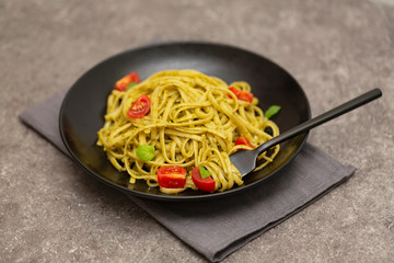 Vegetarian pasta spaghetti with basil pesto and cherry tomatoes.