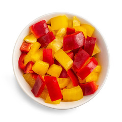 Chopped yellow and red pepper in bowl isolated on white background. Top view