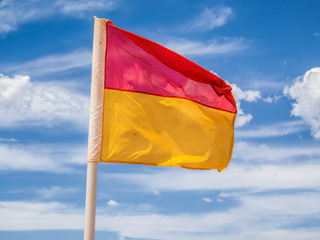 Red and yellow beach safety flag against a cloudy sky