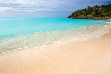 Tropical beach at Antigua island in Caribbean with white sand, turquoise ocean water and blue sky