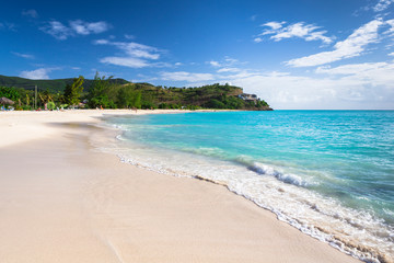 Fototapeta na wymiar Tropical beach at Antigua island in Caribbean with white sand, turquoise ocean water and blue sky