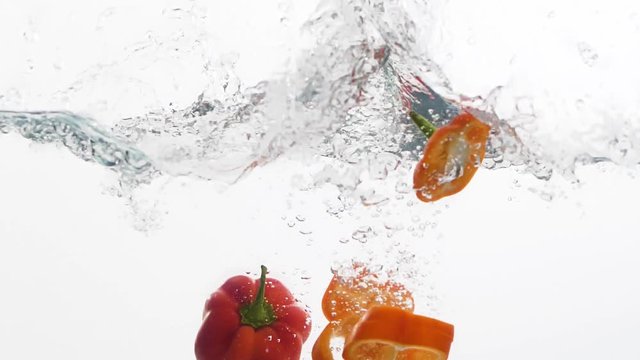 Cuts of peppers falling into a water