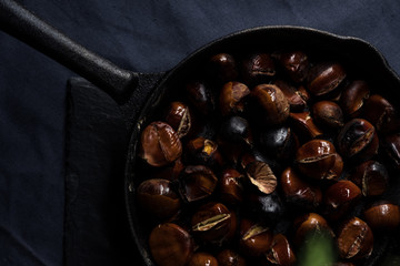 Fried chestnuts served on blue table cloth under Christmas decorated thuja