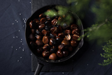 Fried chestnuts with sea salt in rustic pan served on blue table cloth