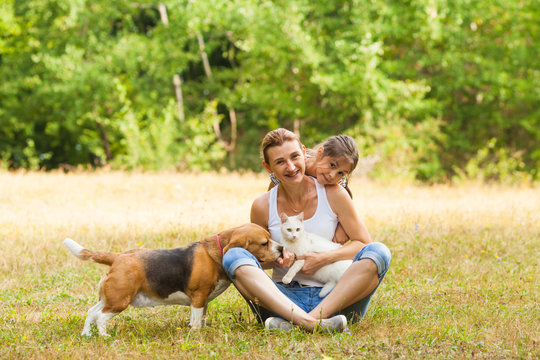Daughter and her mother are smiling while posing with their pets