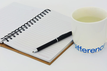 notebook and pen with a cup silkscreen word difference (selective focus)