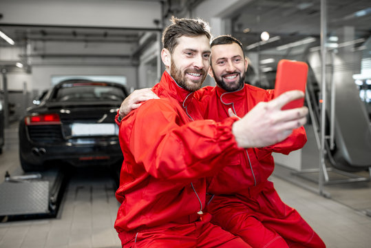 Car service workers in red uniform making selfie photo with phone during a break at the tire mounting service