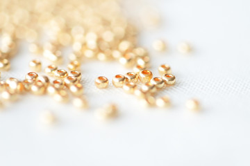 Golden seed beads scattered on textile background close up