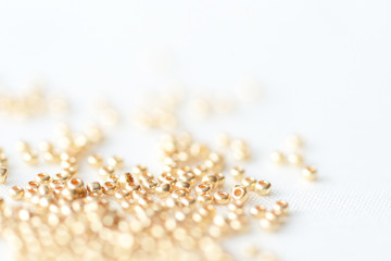 Golden seed beads scattered on textile background close up