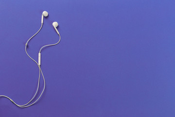 White earphones on violet background