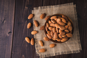 Almonds in a wooden bowl on dark wooden table, Almond  background with copy space