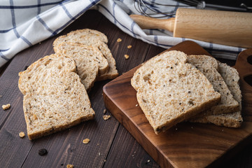 Whole wheat, whole grains bread on dark wooden board, close up, top view