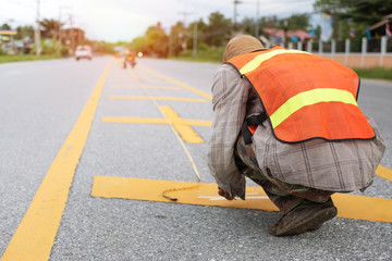 Worker painting the yellow line on the road. Road construction.. with sun light