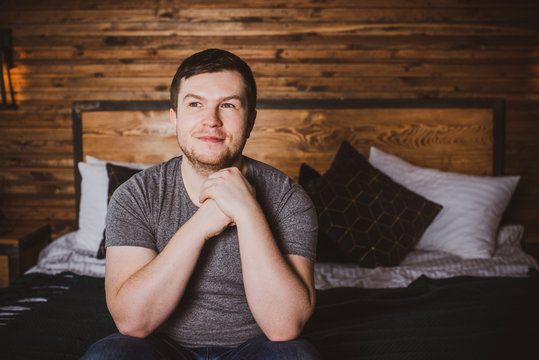 Handsome man is looking away sitting at bedroom in home. Rest and relax after hard work day  