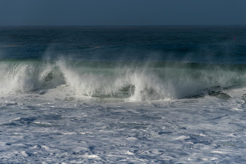 Foamy Atlantic ocean wave on Nazare city beach, Portugal.