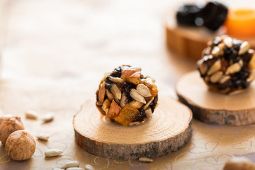 Handmade energy balls on wooden saw cuts and ingredients for their preparation on paper background.