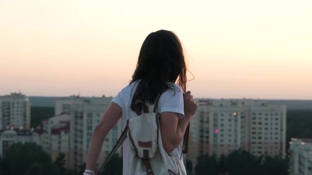 girl puts a backpack on the top of the building.
