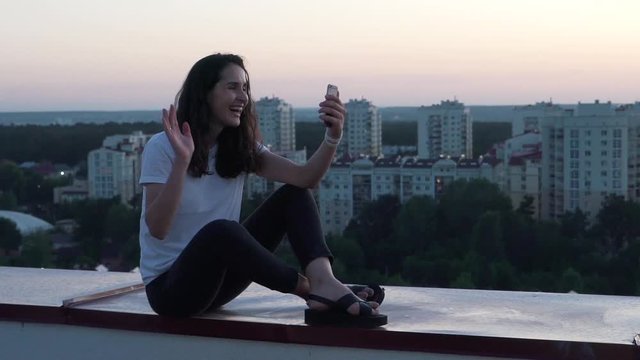 girl communicates by smartphone on the roof of a building.