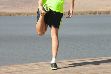 Athletic runner doing stretching exercise, preparing for morning workout in the park 