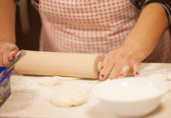 Fototapeta na wymiar Female hands rolling out dough on kitchen table, close up 