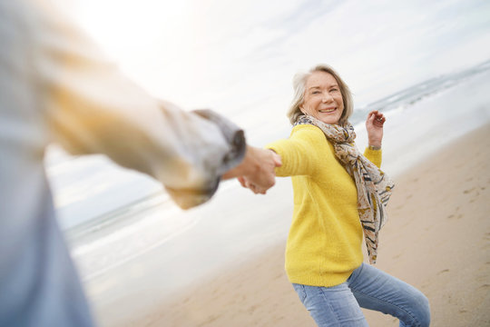 Energetic senior woman holding hands with husband in playful manner