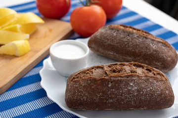 Air black buns with  black bunson a white plate, on a background of lemons and tomatoes