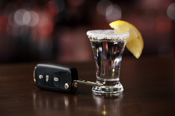 The concept of a DUI. Law hammer, alcohol and car keys on wooden table, dark background