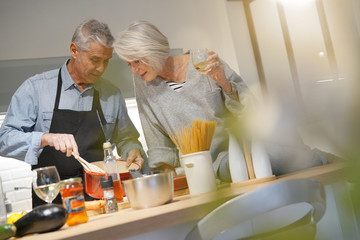 Fototapeta na wymiar Senior couple couple cooking together in modern kitchen