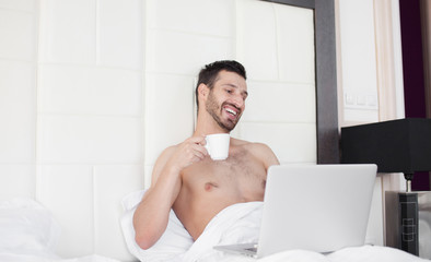 Bearded man in bed drinking morning espresso coffee in sunrise light